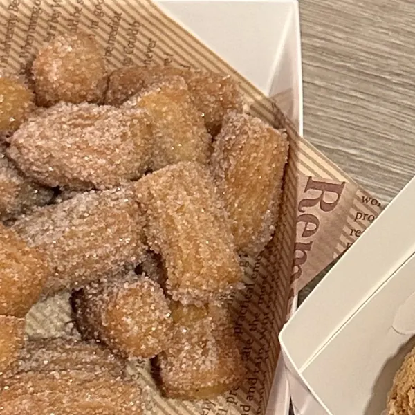 Churros bites bertabur gula kayu manis dalam wadah kertas