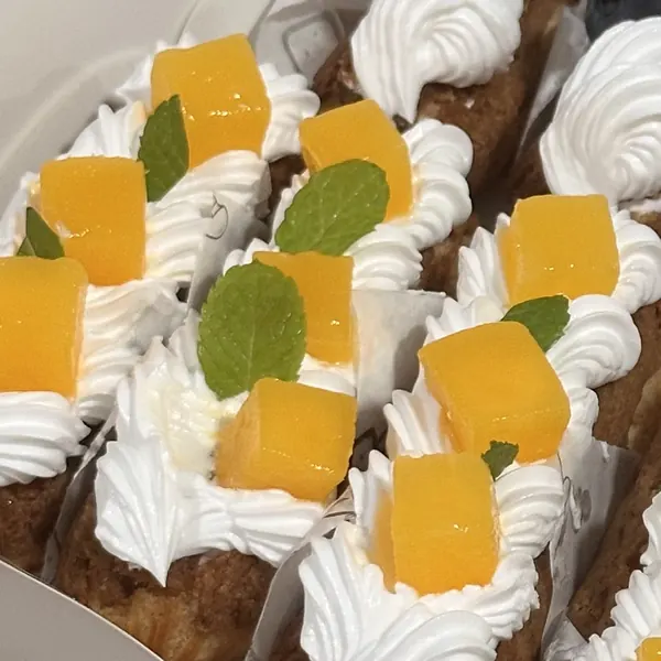 Éclair dengan whipped cream, potongan mangga, dan daun mint